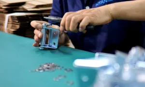 Factory worker manually assembling a heavy-duty industrial spring hinge on the production line