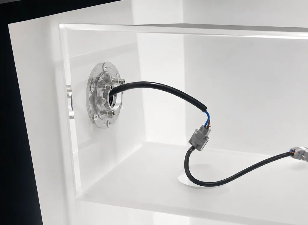 Stainless steel disc-type 360 degree swivel torque hinge mounted in a celling light, with the supply cable routed through the central bore