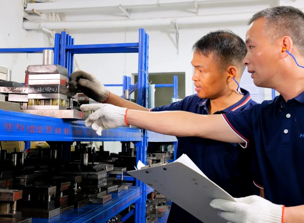 Workers checking hinge tooling molds against a drawing at a custom hinge factory
